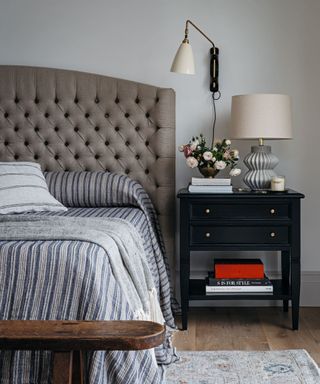 bedroom with brown headboard and striped bedding and bedside table with lamp