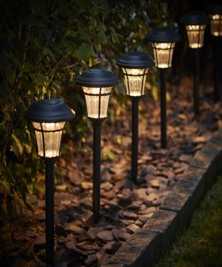 Row of lantern lights at night in a narrow garden