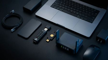 A selection of security and privacy-focused home office essentials on a desk next to a MacBook