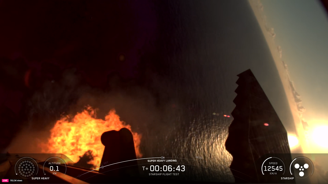 A giant booster fires its engines to land before splashing down in the ocean