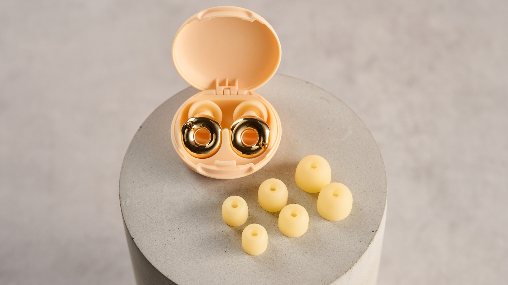 The Loop Switch 2 earbuds are sitting in their open case. Three pairs of different-sized tips are arranged in front of them.
