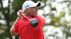Lee Westwood, wearing a red polo and white cap, holds his finish on a drive