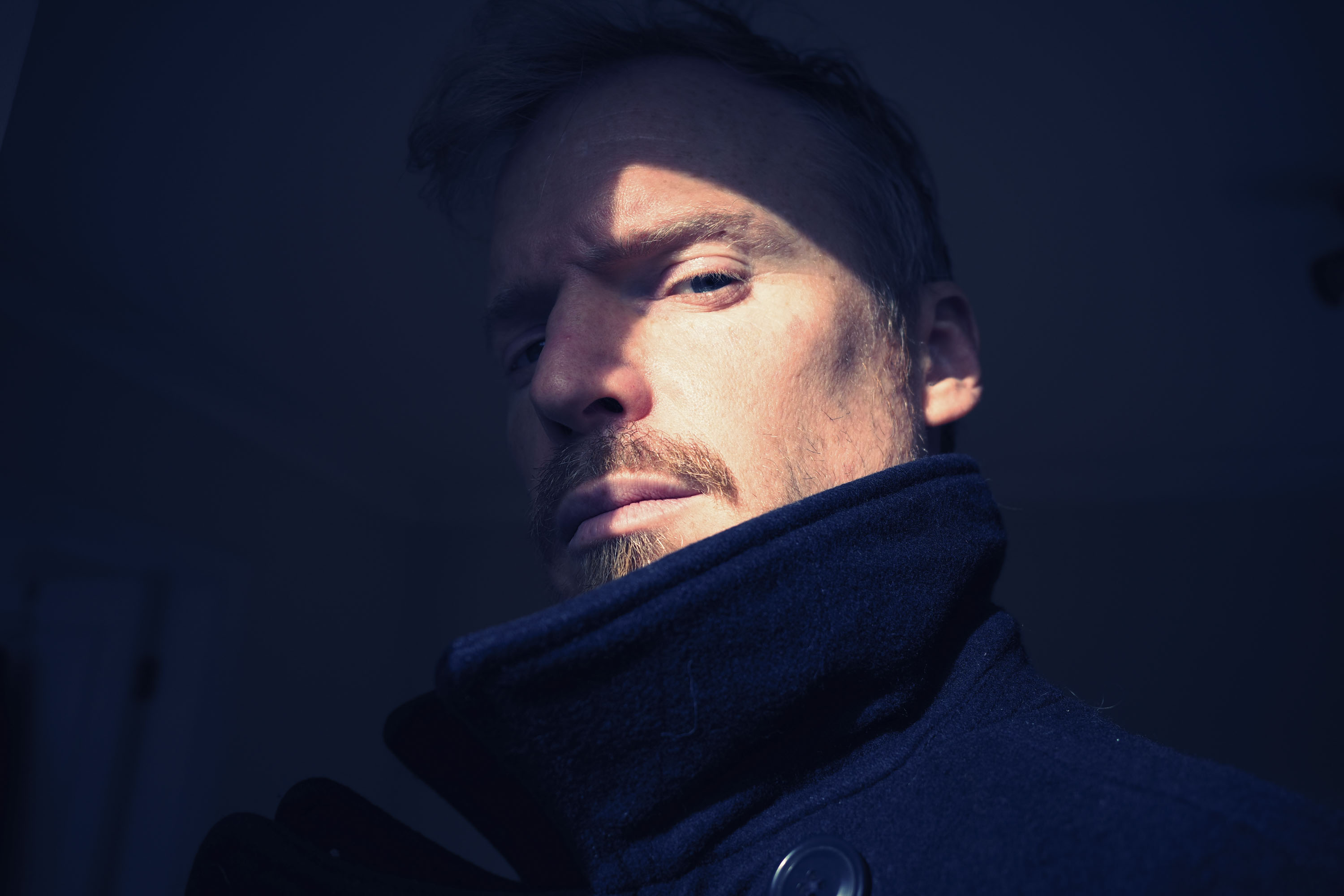 Ricoh GR IV sample gallery: man in winter jacket with a patch of light illuminating one side of his face