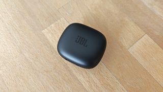 JBL Live Pro 2 review: headphones charging case on a wooden table