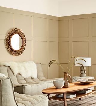 beige panelled living room with sofa and woven round mirror