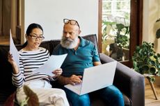 A couple discussing their finances sitting on a couch with a laptop