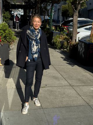 Irene Chen wearing pinstripe trousers with wool coat and large printed scarf.