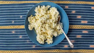 overhead shot of marinated feta on a blue plate and tapestry