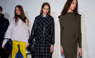 Three models, one wearing a white knitted sweater and a yellow and blue skirt, one wearing a black and white check jacket and skirt, and one wearing a brown knitted dress