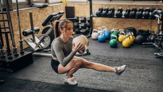 Woman doing weighted pistol squat in a gym