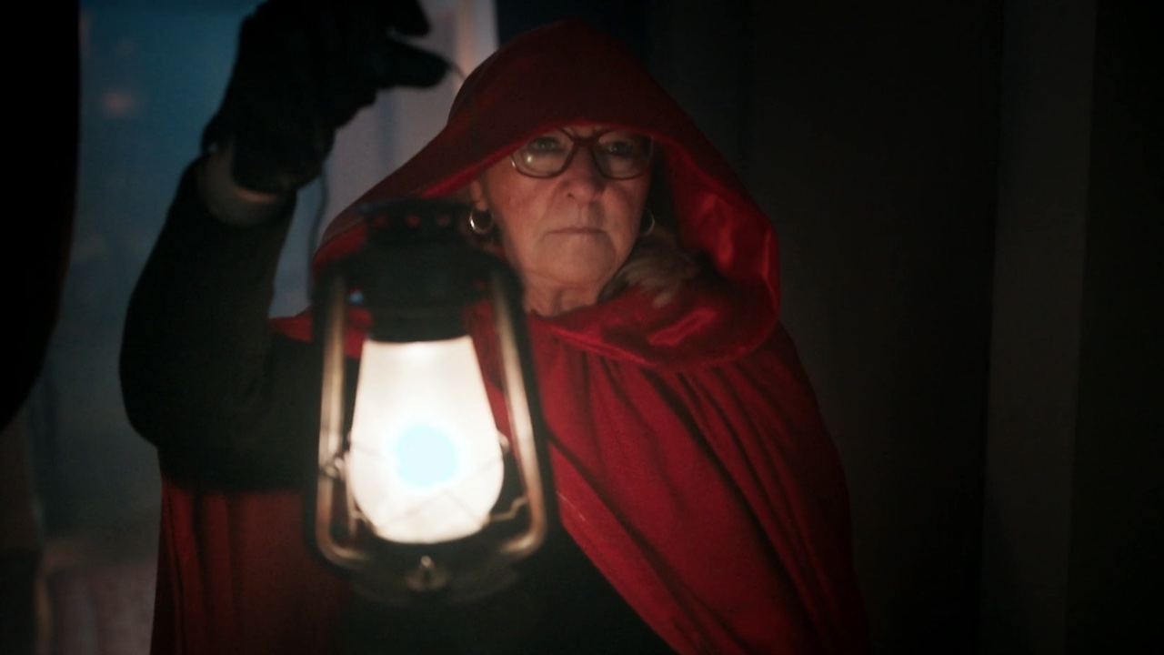 Donna Kelce walking in a cloak with a lantern.