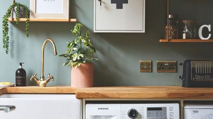 Wooden kitchen worktop with brass taps above the kitchen sink and brass plug sockets