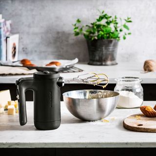 white kitchen counter with black hand mixer, silver mixing bowl, and ingredients