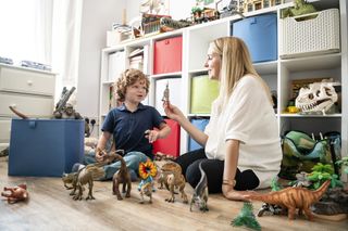 Mum sitting with child on the floor while sorting dinosaur toys together