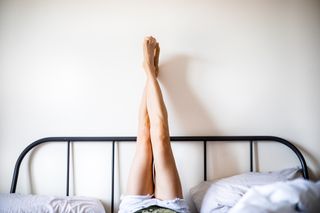 Why is sex painful? Woman with Legs Raised wearing white shorts lying on bed