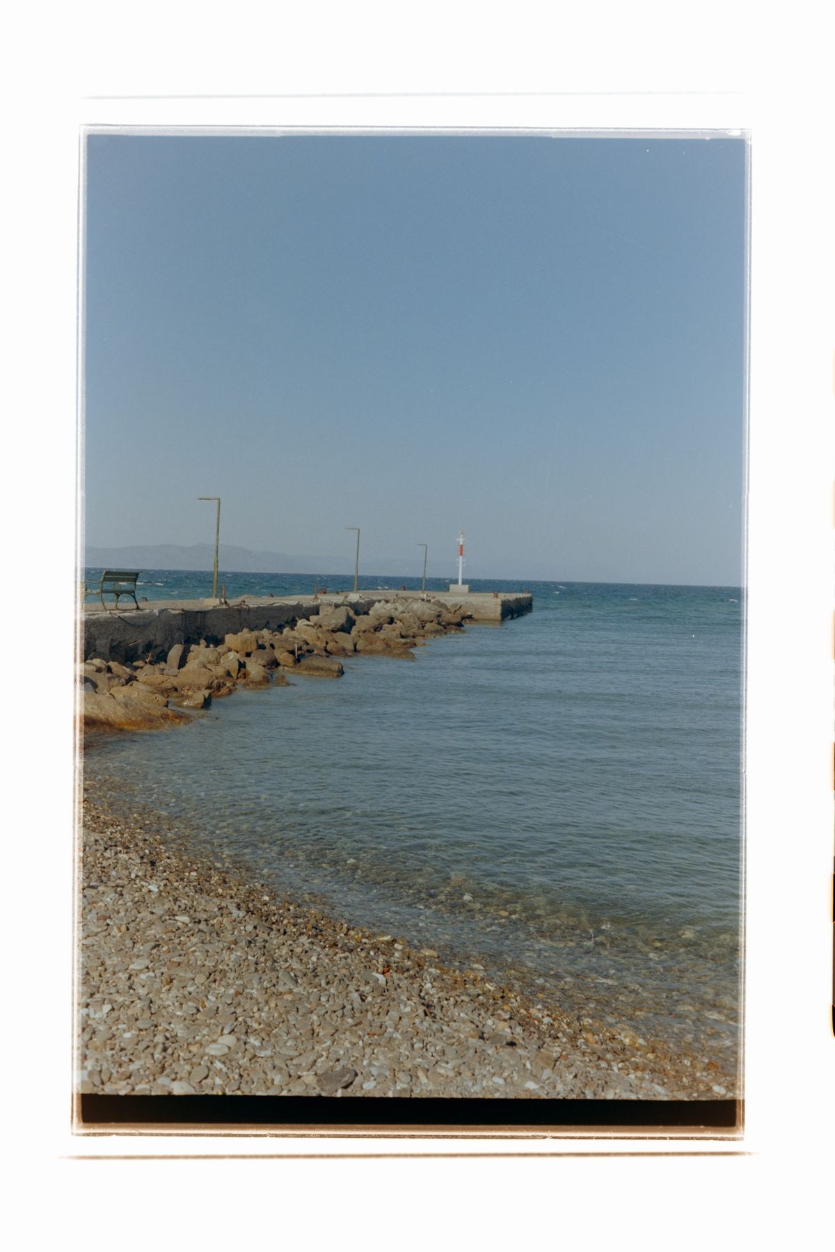 A lighthouse at the end of a jetty surrounded by water