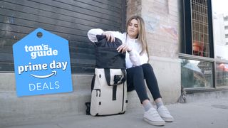 A women in a city sitting next to her Wanrd Prvke Lite Travel Backpack in off white