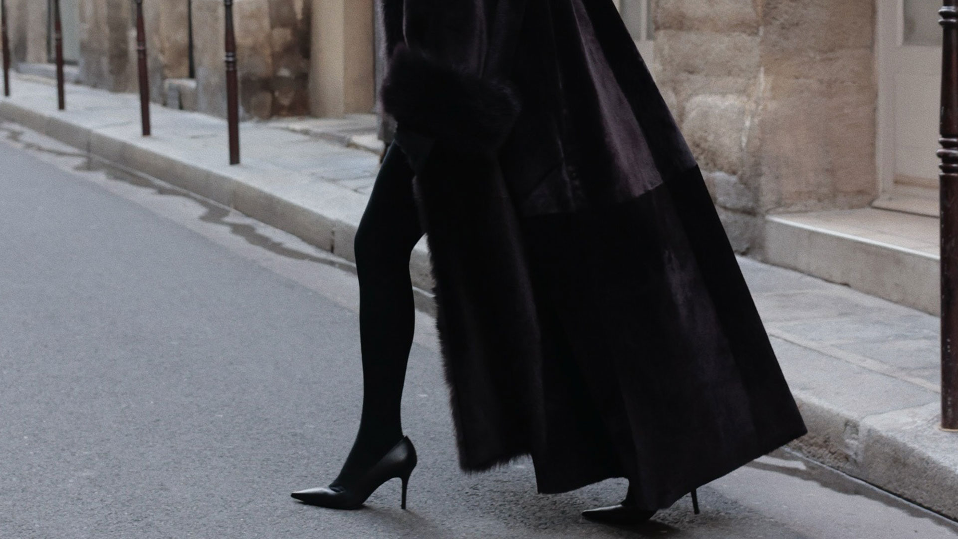 @modedamour wearing an all black outfit with a fur coat, black tights, and pumps. 