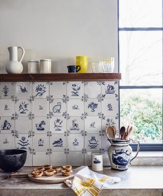 A close-up shot of blue and white kitchen wall tiles behind some freshly baked pastries on the worktop