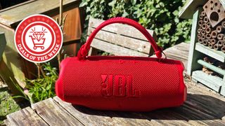 JBL Charge 6 wireless speaker in red on a wooden table outside