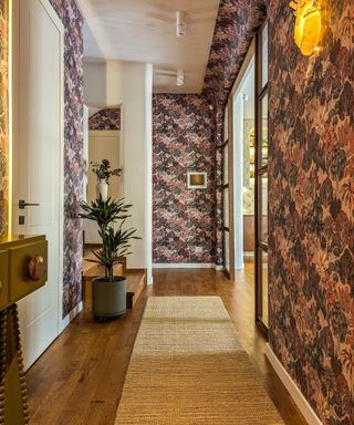 hallway with dark patterned wallpaper and wooden floor with rug