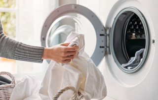 Hand pulling white laundry out of washing machine