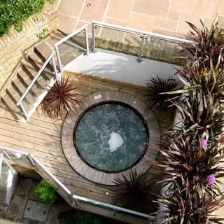 outdoor hot tub with glass handrail and surrounding plants