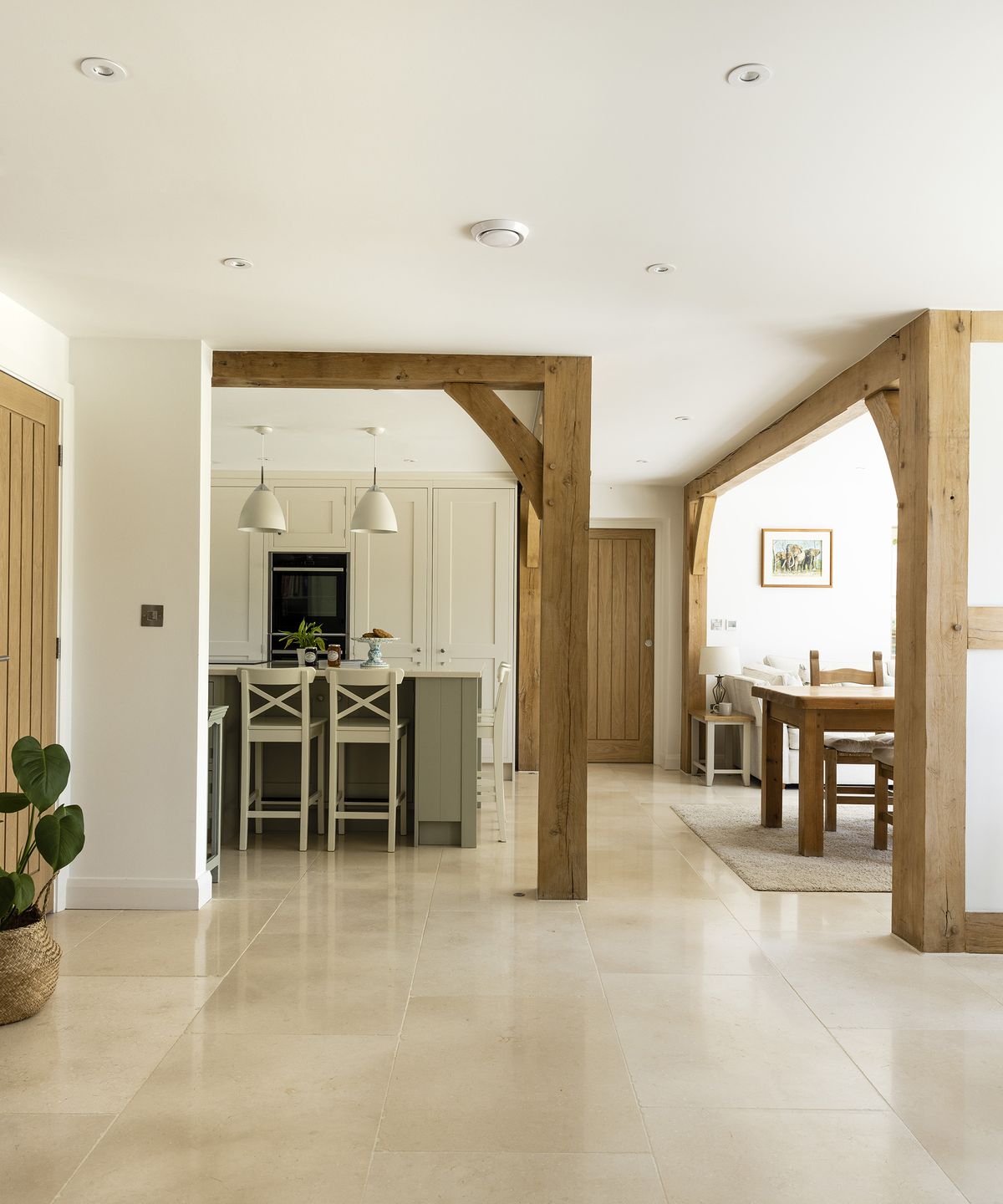 An open plan downstairs in a farmhouse style new build home with exposed timber frame and light interiors