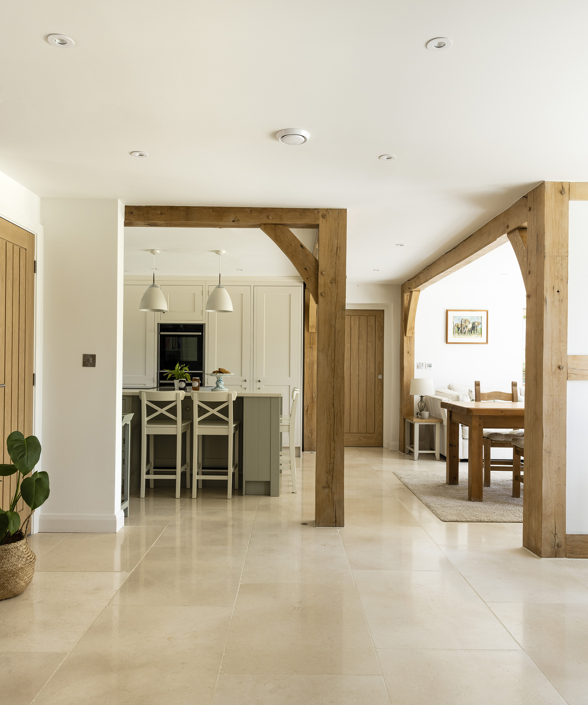 An open plan downstairs in a farmhouse style new build home with exposed timber frame and light interiors