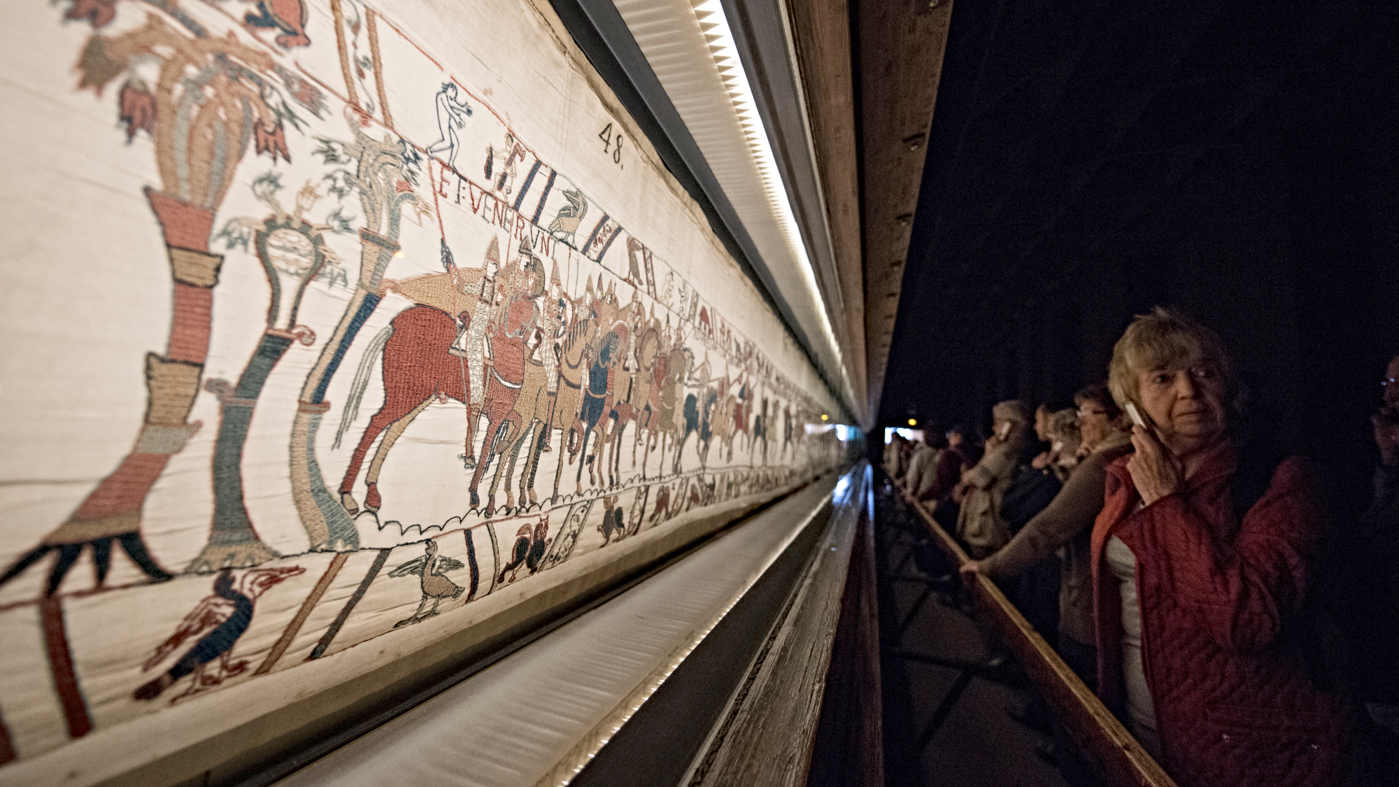 People looking at the Bayeux Tapestry on display in Bayeux