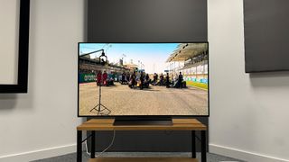 LG C4 (OLED48C4) 48-inch TV straight on view in corner of test room with F1 race on screen