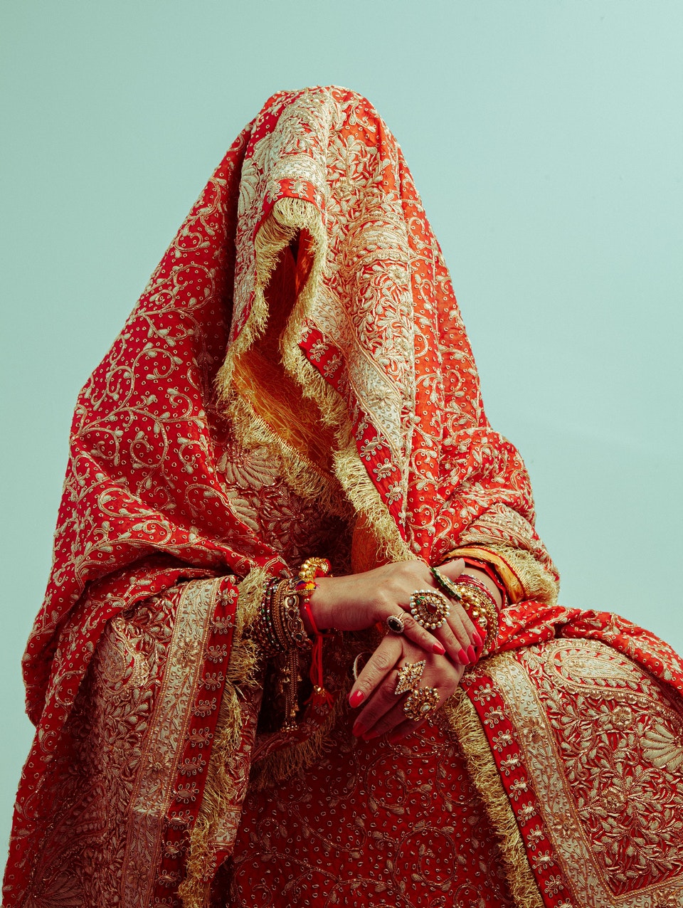 A person completely shrouded in a red and gold cloth