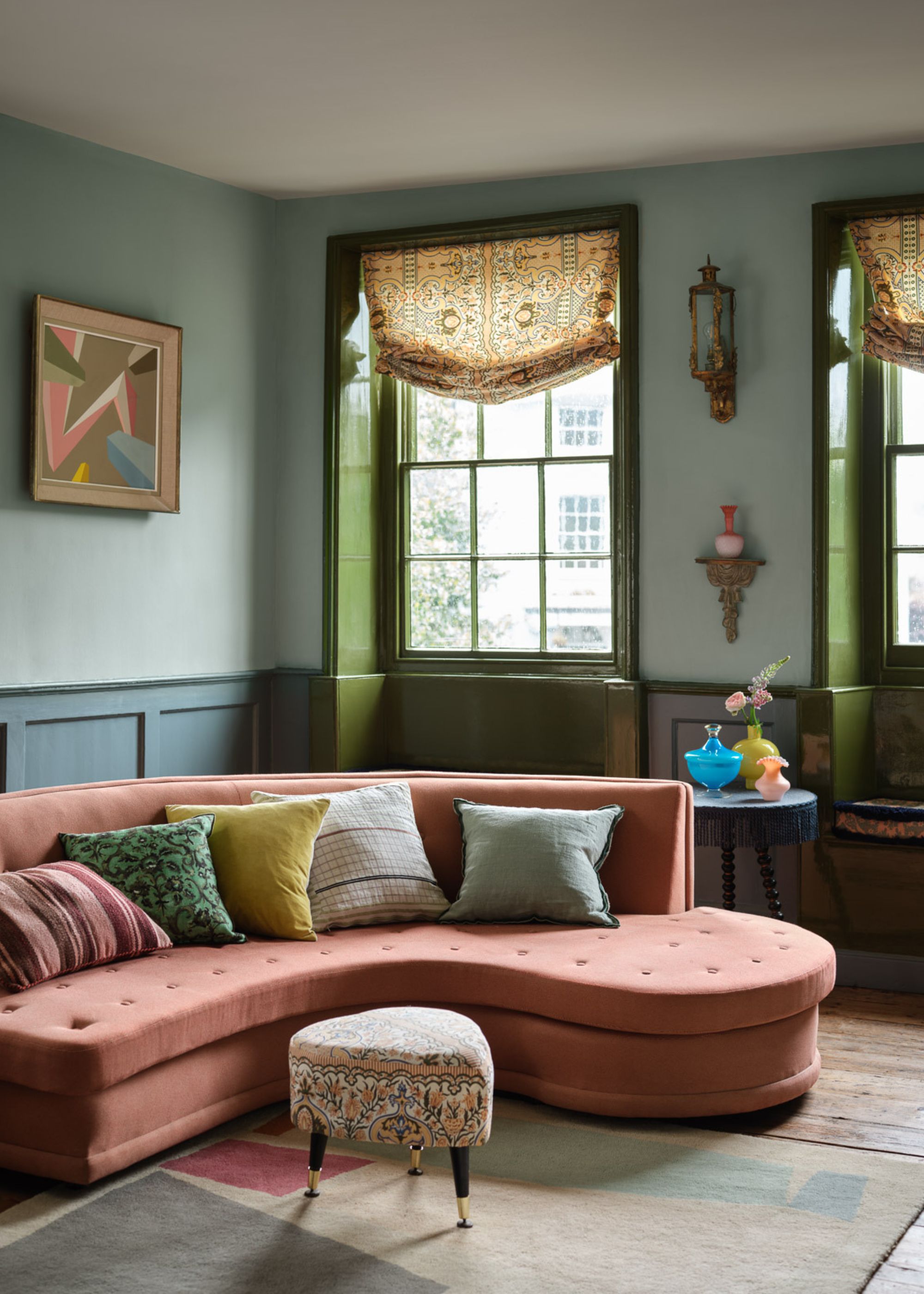 A cozy living room with a split complementary color scheme, with a terracotta sofa, blue-green walls, and yellow-green cushions.