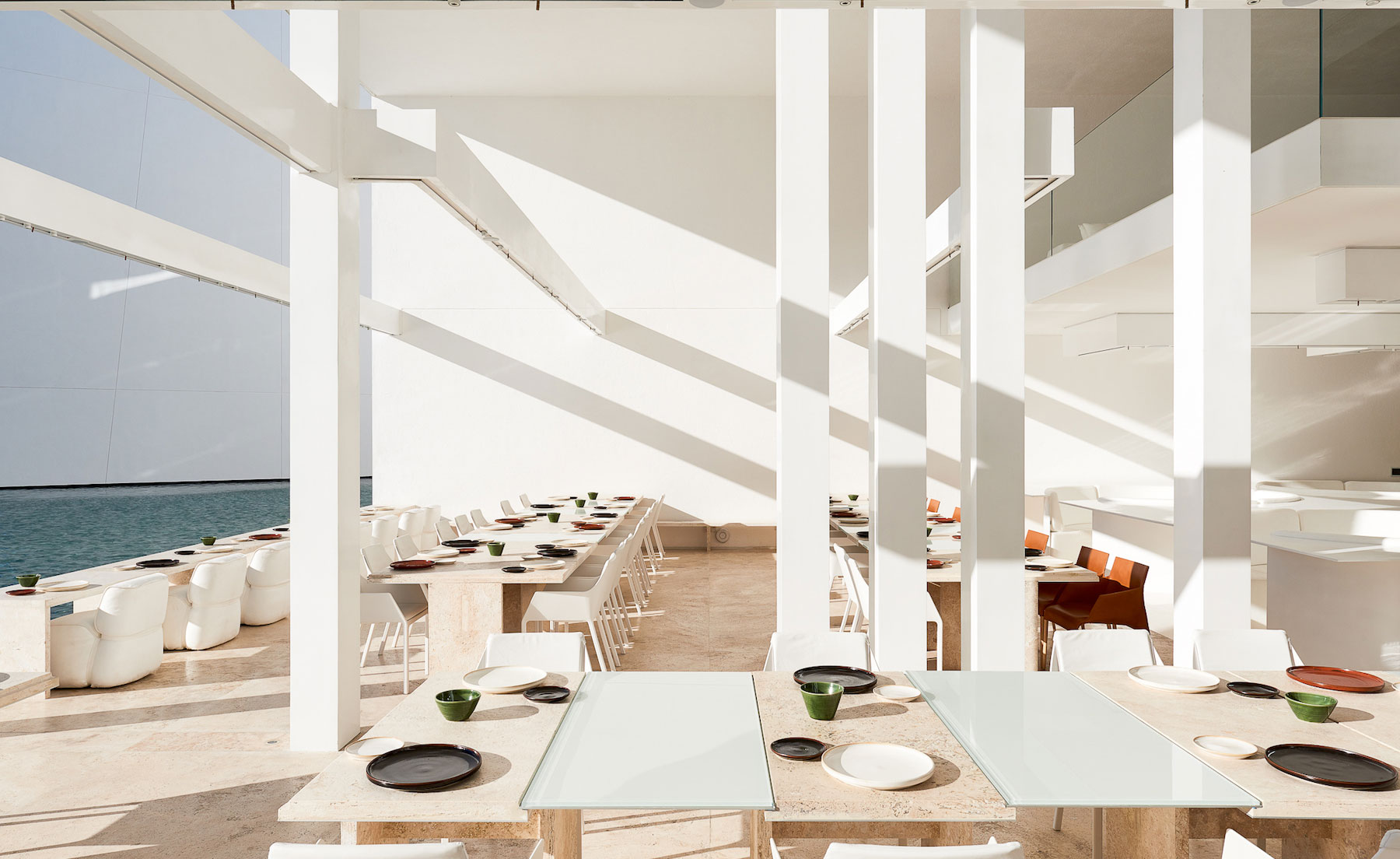 Restaurant seating area outside on patio, white tables and chairs match the building colours