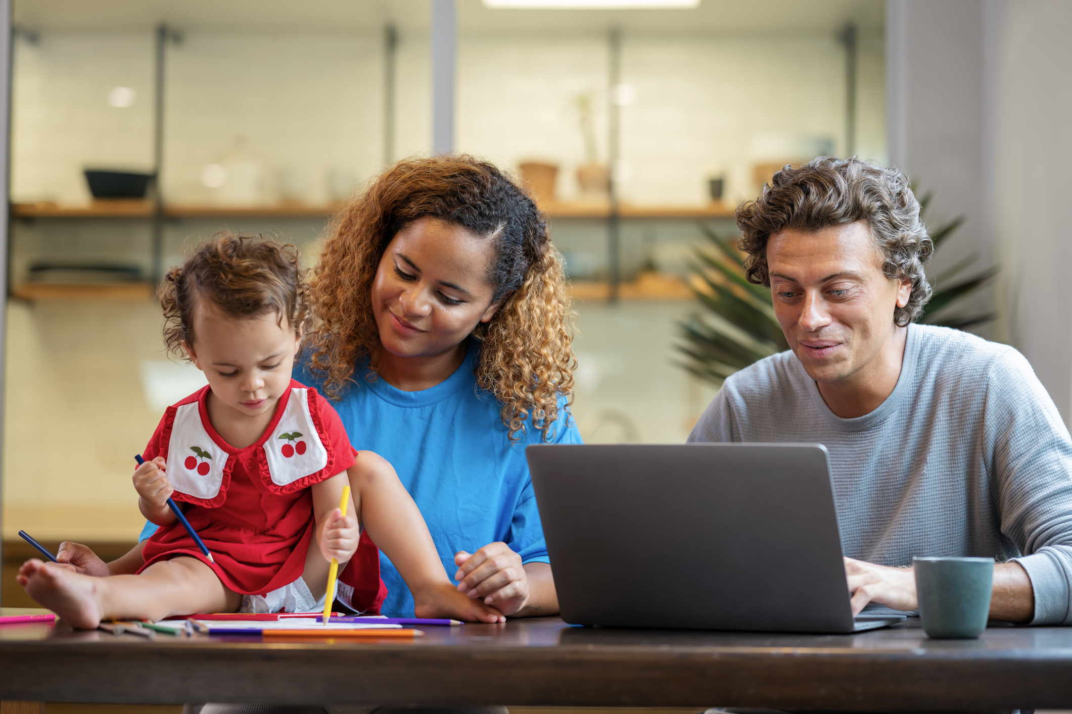 Father using a laptop computer for online meetings in the residential living rooms while his wife was teaching her daughter how to draw on the side.
