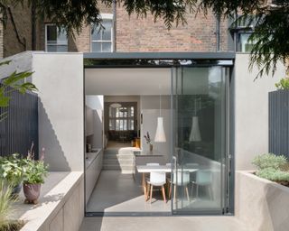 Wraparound extension seen from garden with dining table and kitchen and sliding doors, and view through to front of house