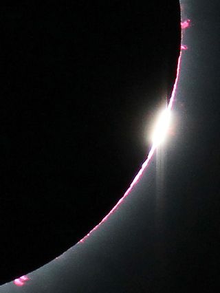 A close-up view of the diamond ring and pink solar prominences protruding from behind the moon’s disk during the July 11, 2010, total solar eclipse. Prominences are immense glowing features that extend many thousands of miles from the sun. 