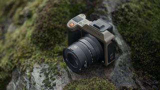 The Hasselblad X2D 100C Earth Explorer Edition camera and lens sitting on a mossy, rocky outcrop