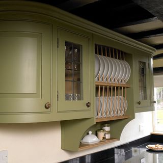 Green cabinet with plates and white wall