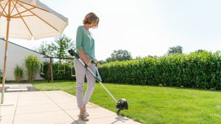 Bosch UniversalGrassCut 18–26 cordless strimmer being used to edge a lawn