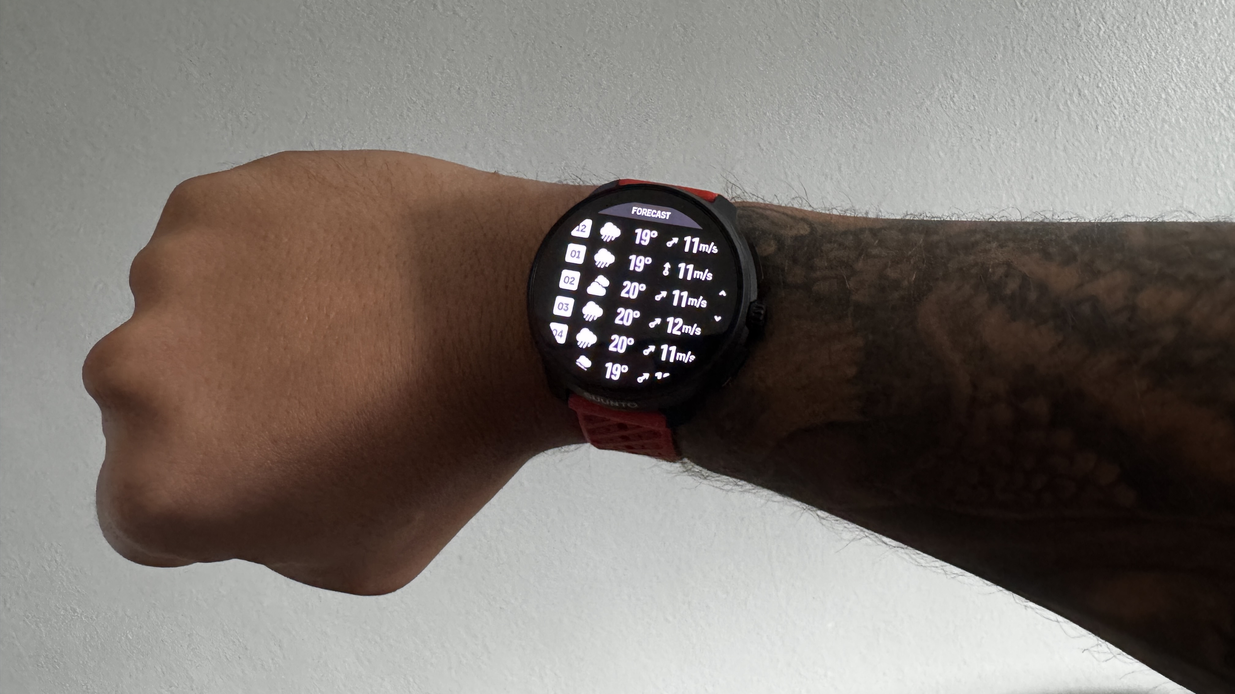 The Suunto Race 2 watch on a wrist showing the weather forecast