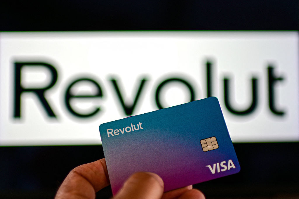 Revolut card held in front of Revolut sign