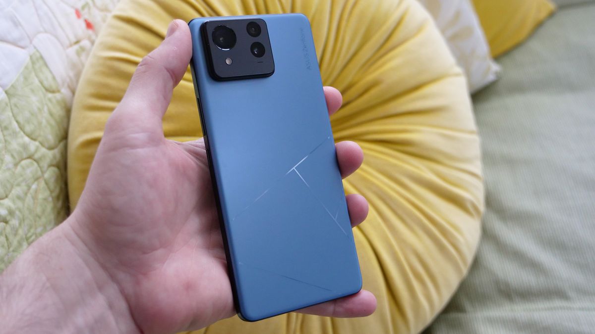 Asus Zenfone 11 Ultra in Skyline Blue with the back facing the camera being held above a couch