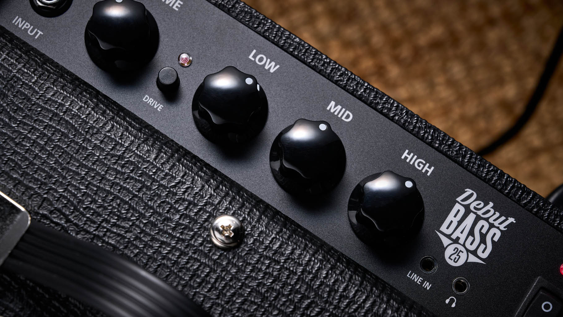 Blackstar Debut Bass 25: this compact little combo is finished in black with matching grille clothe and is photographed in close-up against a stone floor and weaved rug.