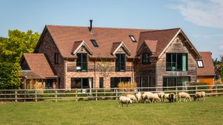 A large two storey timber frame home with field and sheep out in front