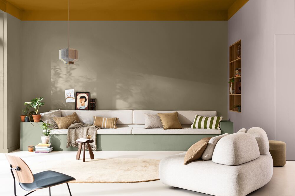 Image of a modern living room with a built-in sofa on the back wall. The walls are a color blocked combination of sage green, olive, burnt orange, and dusty pink.