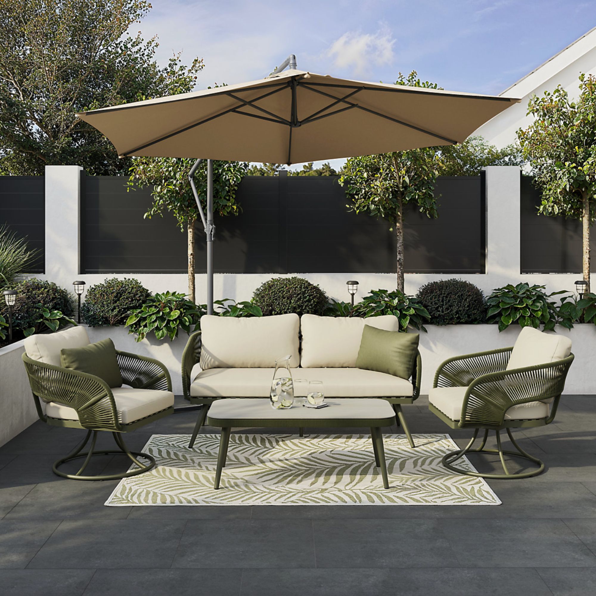 GoodHome Giza Green Metal 4 Seater Coffee set in garden on black decking with large parasol and green and white rug