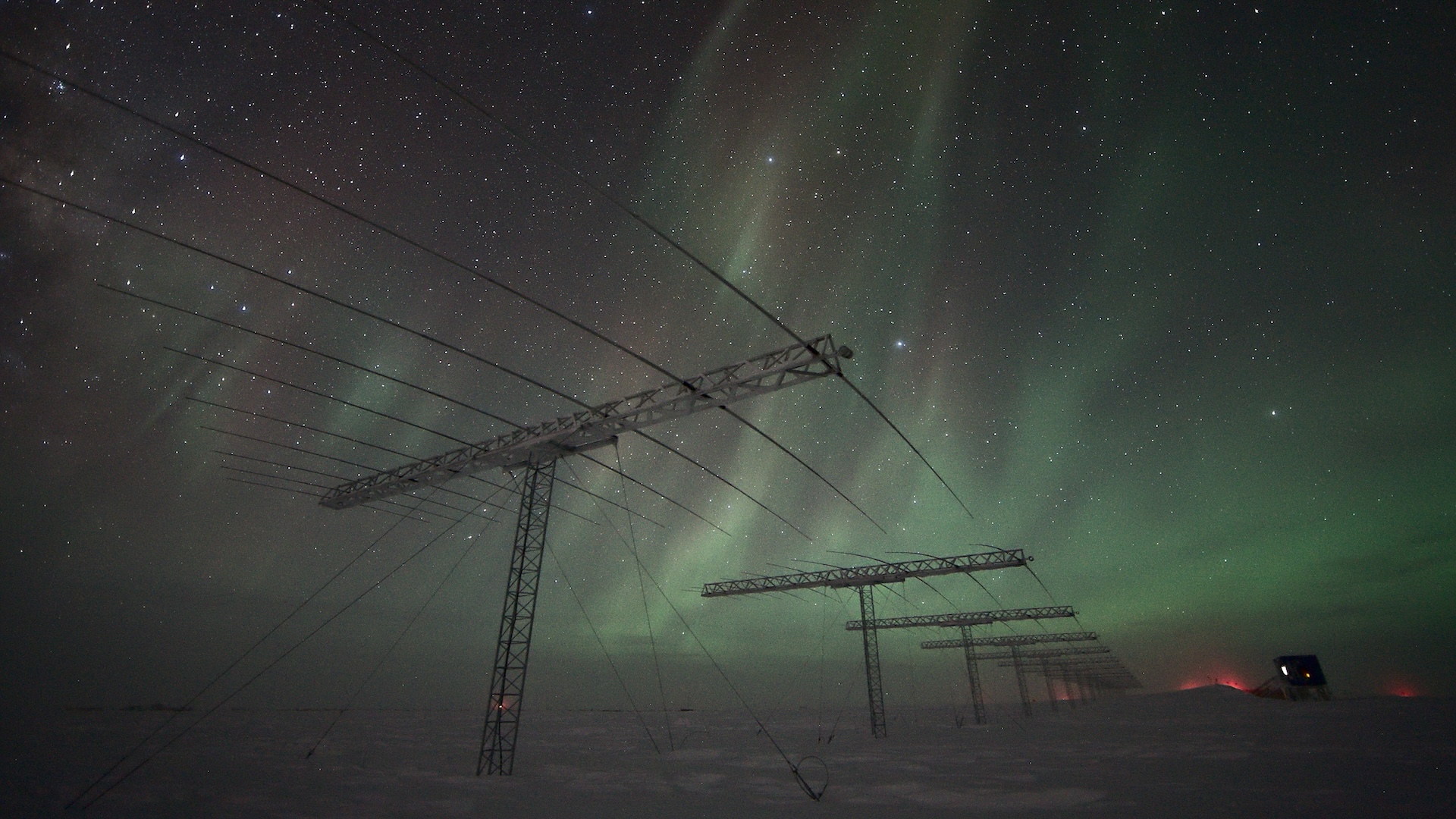 A photo of auroras over the South Pole with antennas and electrical wires visible