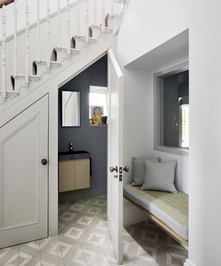 An under stairs idea with a blue powder room with wooden vanity inside cupboard under stairs