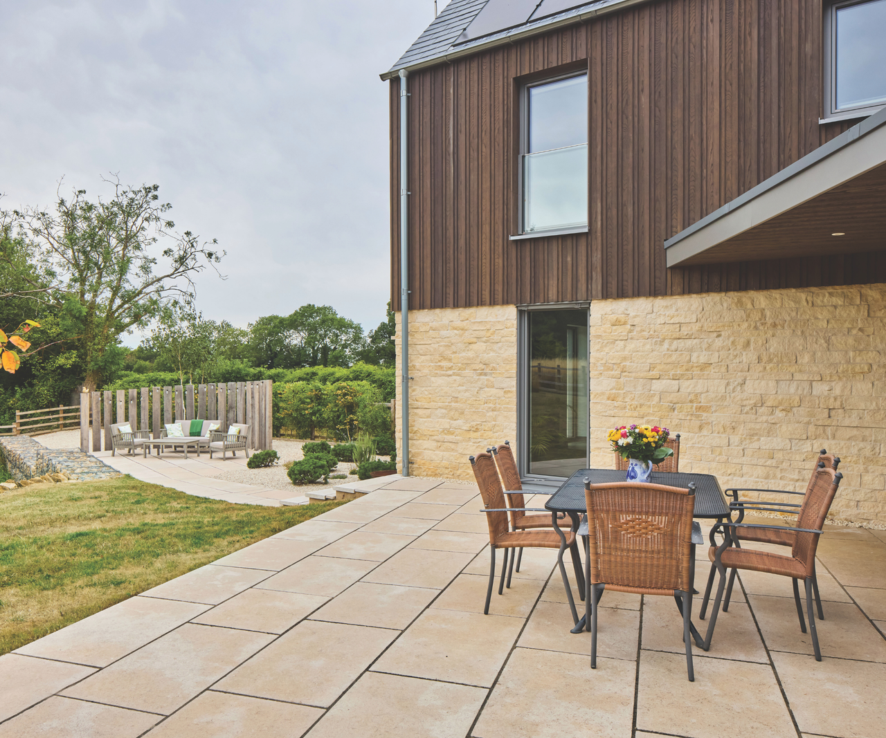 Patio area outside wood clad and stone brick house